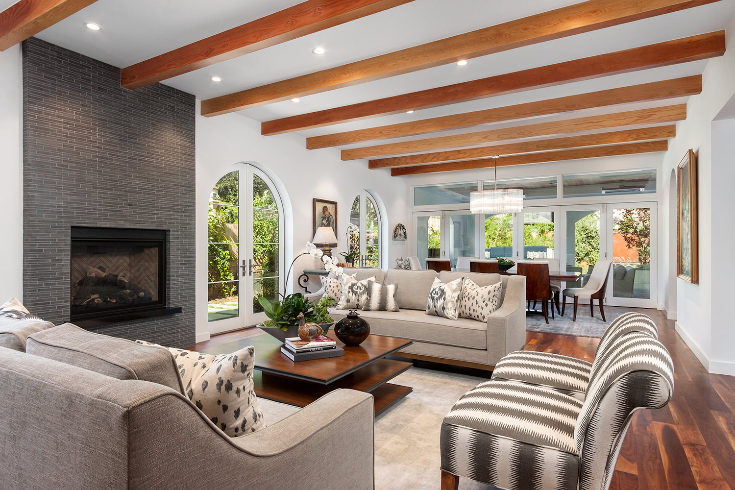 living room with fireplace and grey stone wall accent. White wall and exposed wooden beam ceiling and wood flooring