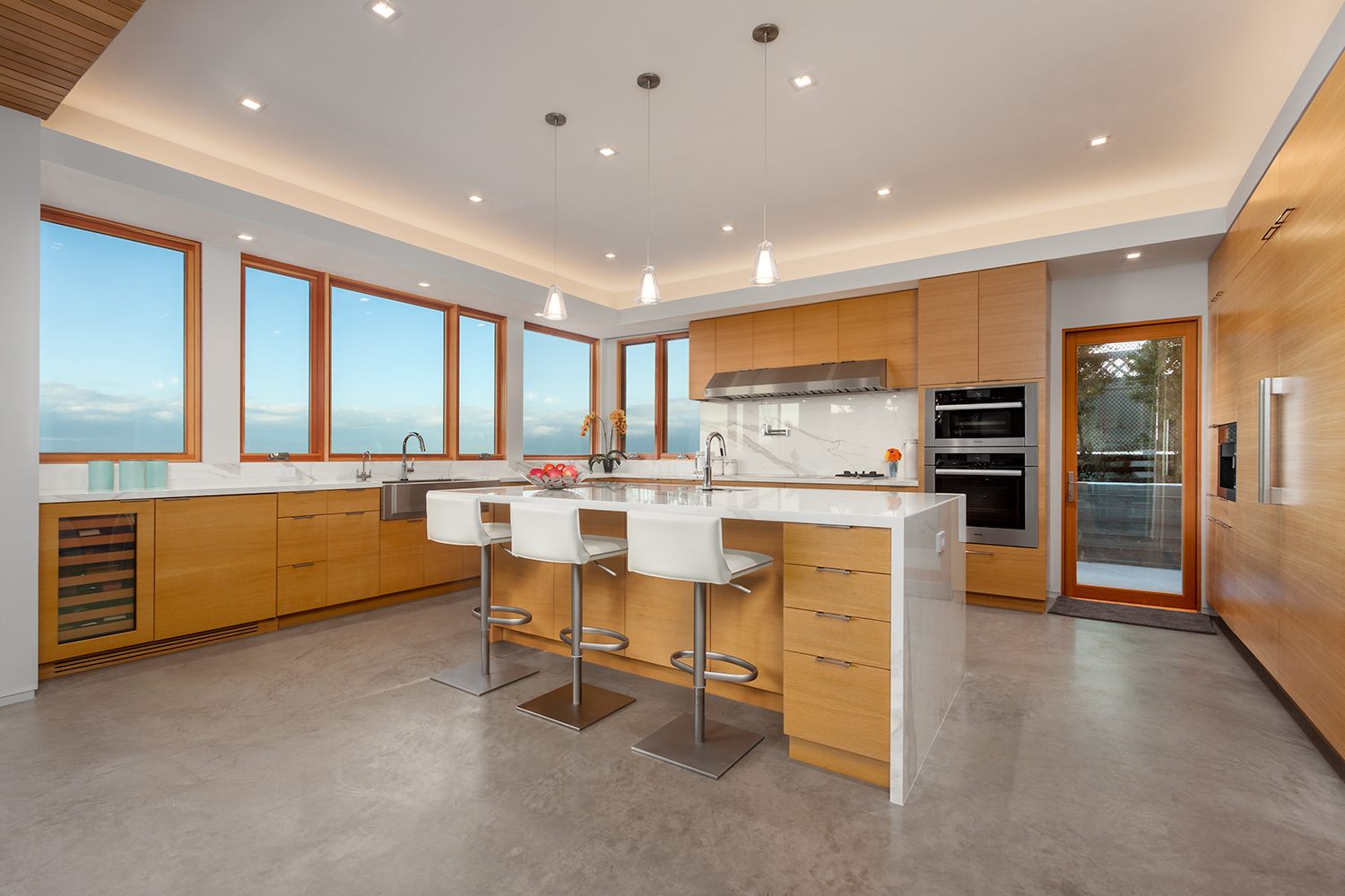 contemporary kitchen with white marble and wood cupboards with large windows